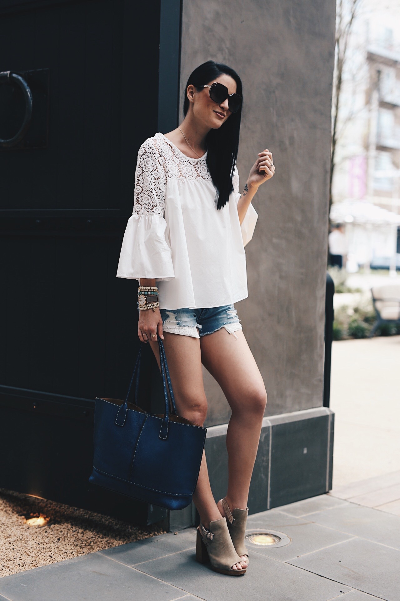 White Crochet Blouse featured by top US fashion blog Dressed to Kill; Image of a woman wearing Chicwish top, American eagle cut off shorts, Frye shoes and tote. 