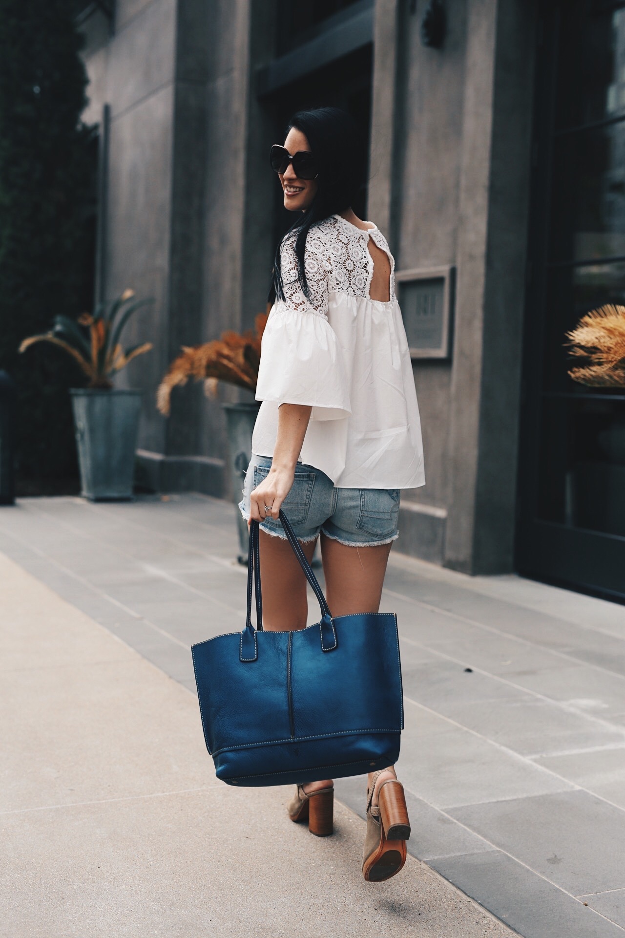 White Crochet Blouse featured by top US fashion blog Dressed to Kill; Image of a woman wearing Chicwish top, American eagle cut off shorts, Frye shoes and tote. 