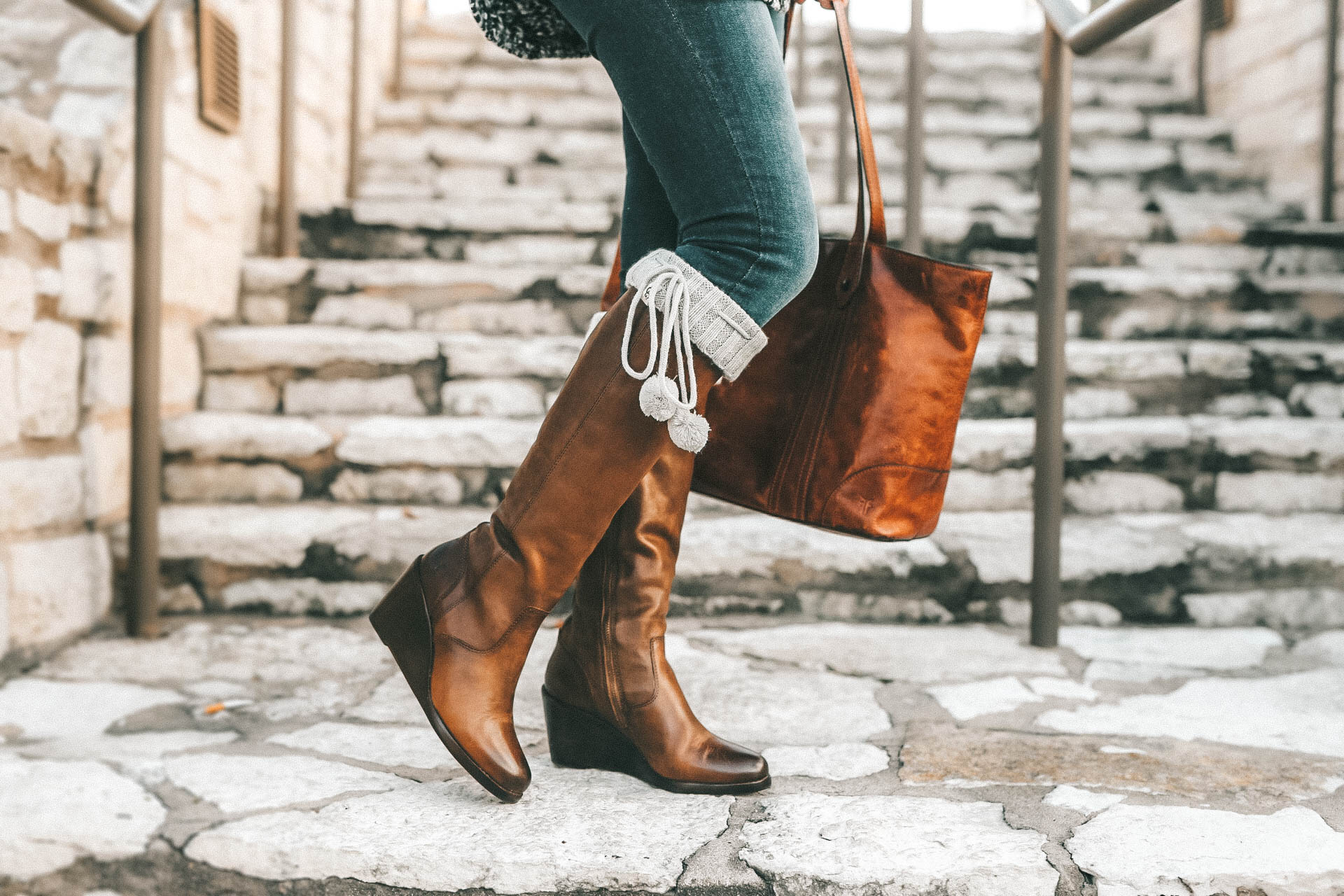 DTKAustin is sharing the best investment boots for Fall and Winter with Frye and Zappos. Ashley is wearing Knee high pom pom socks from UGG, skinny jeans from Levis, a chunky knit beanie from Sole Society, Melissa Frye Tote and a knit sweater from Nordstrom. || Dressed to Kill #winterboots #womensboots #fryeboots #dtkaustin