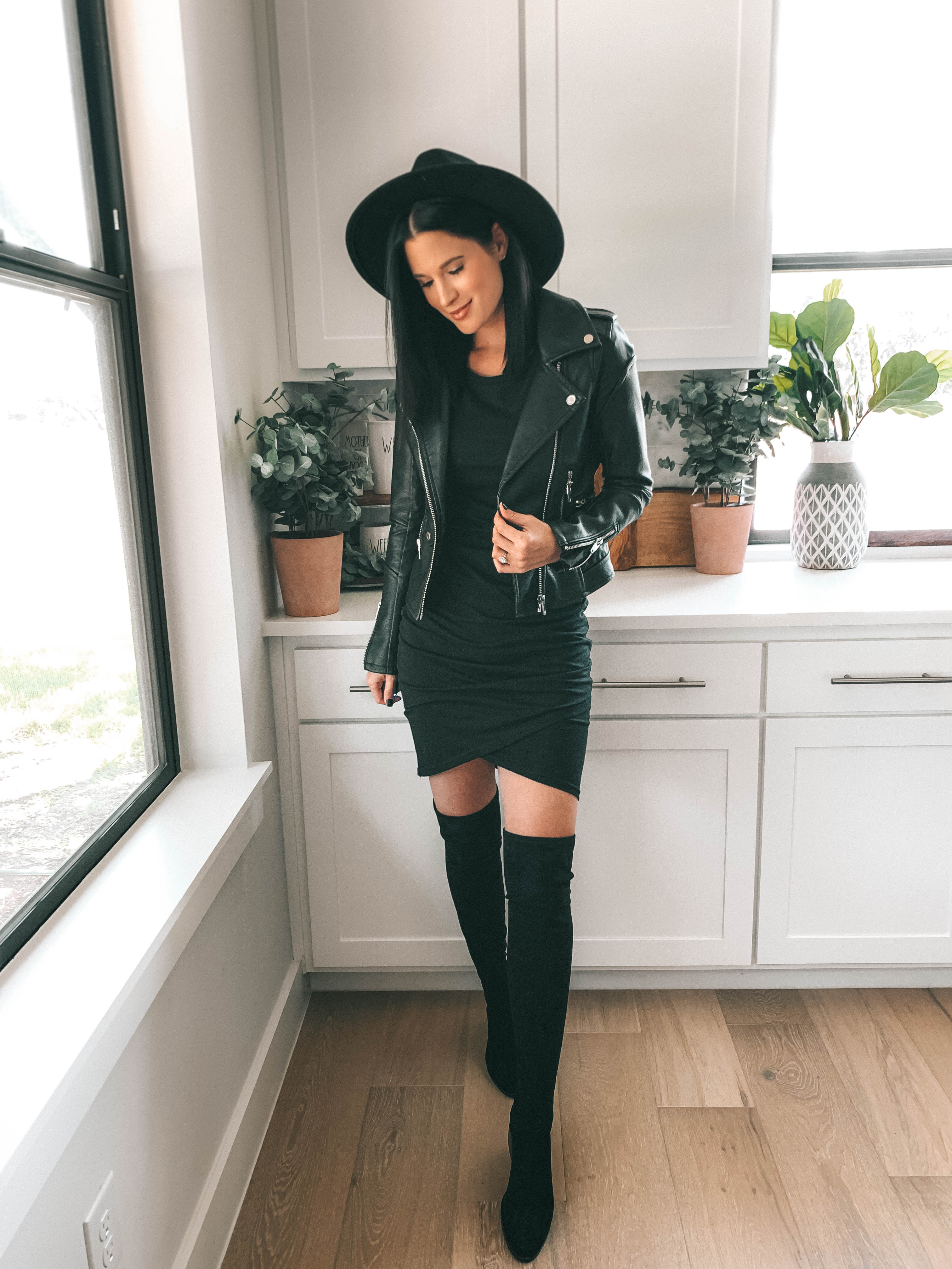 How to Style an All Black Outfit 3 Different Ways by popular Austin blog, Dressed to Kill: image of woman standing in her kitchen and wearing a black Leith Ruched Body-Con Tank Dress and black BLANKNYC Record Breaker Collarless Faux Leather Moto Jacket, 