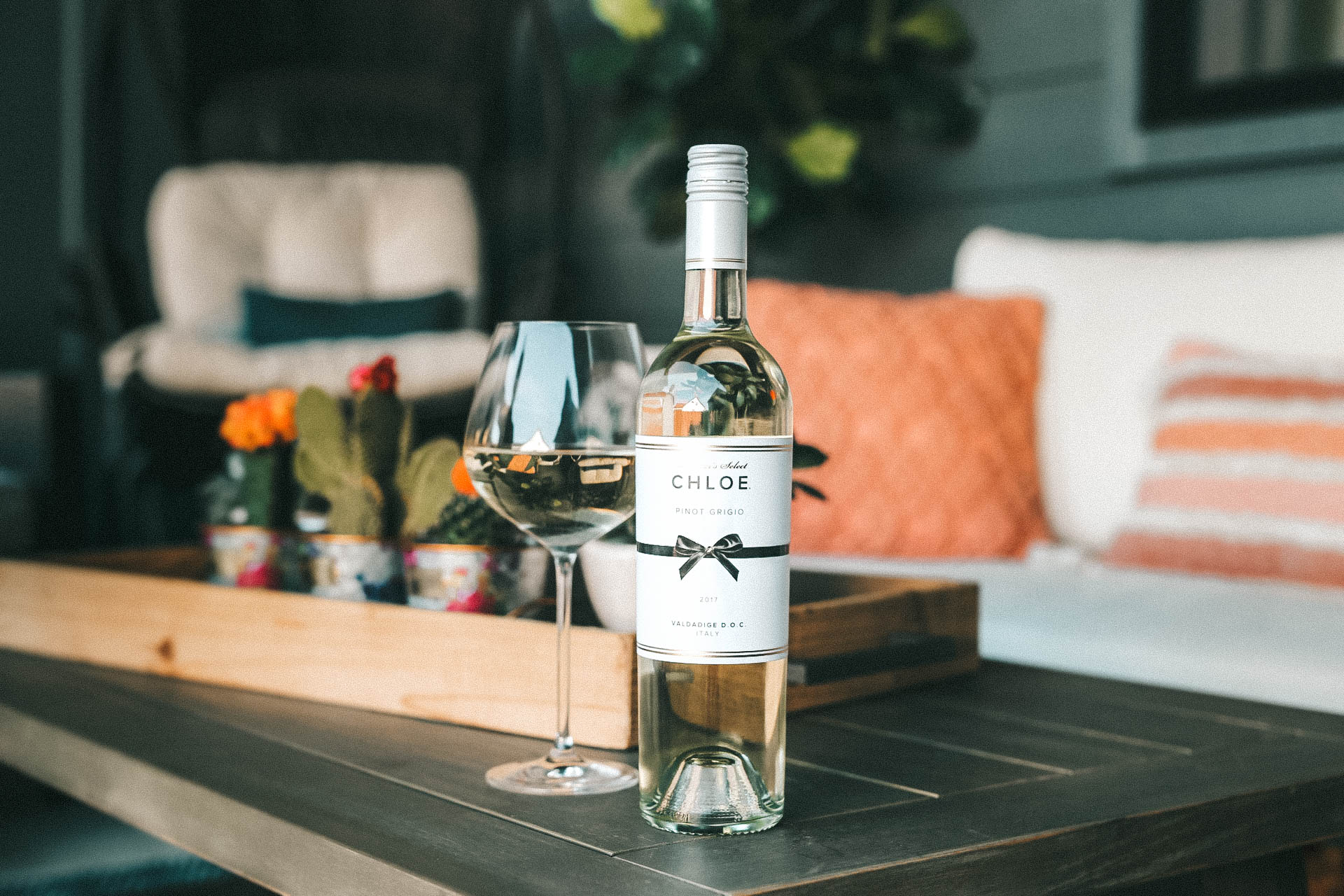 Celebrating Women in Film with Chloe Wine Collection by popular Austin life and style blog, Dressed to Kill: image of a bottle of Chloe pinot grigio wine on a wooden coffee table with a wine glass resting next to it.