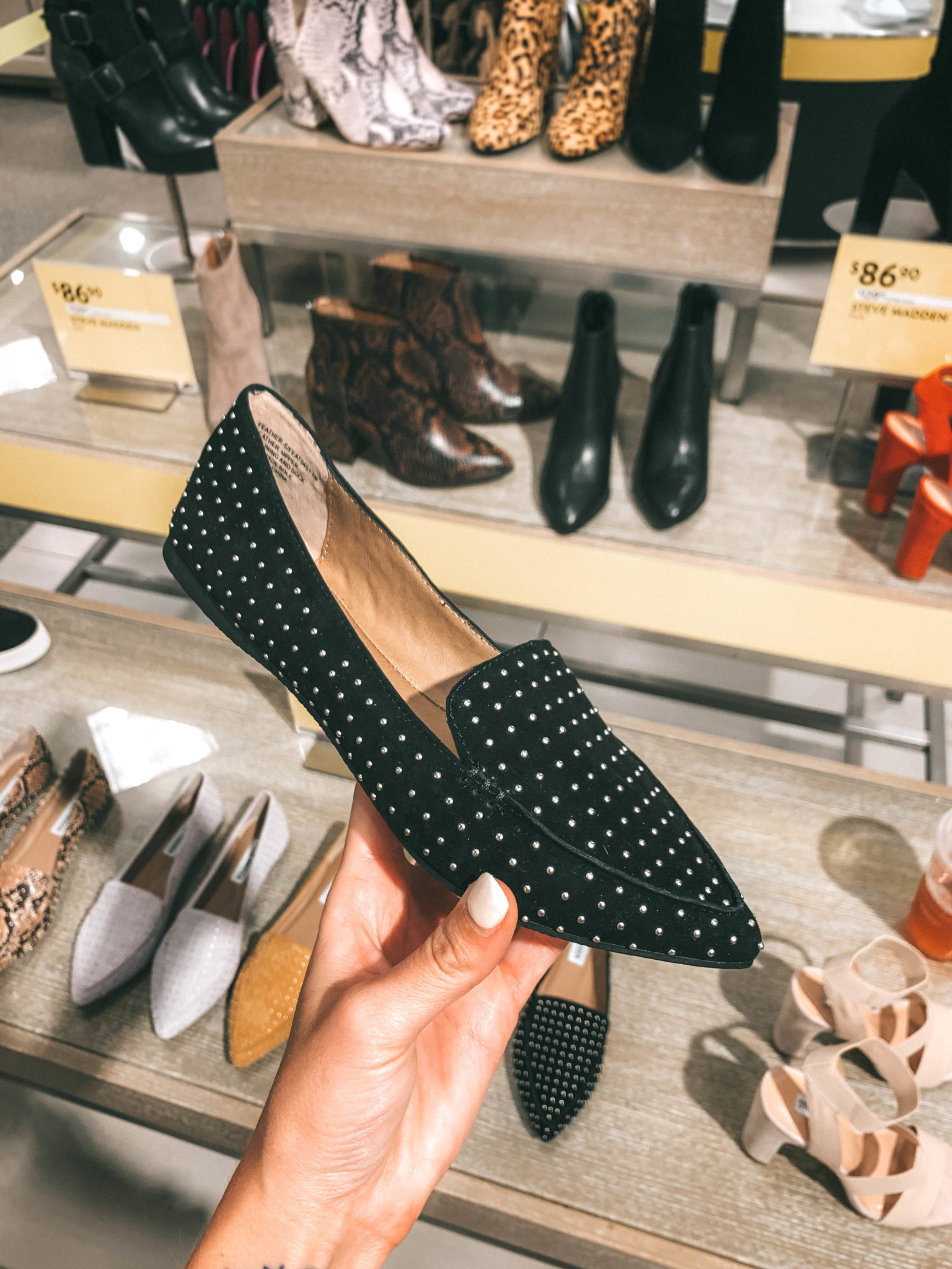 Top 11 Must Have Pieces from the Nordstrom Anniversary Sale by popular Austin fashion blog, Dressed to Kill: image of a woman holding a pair of black studded loafers.