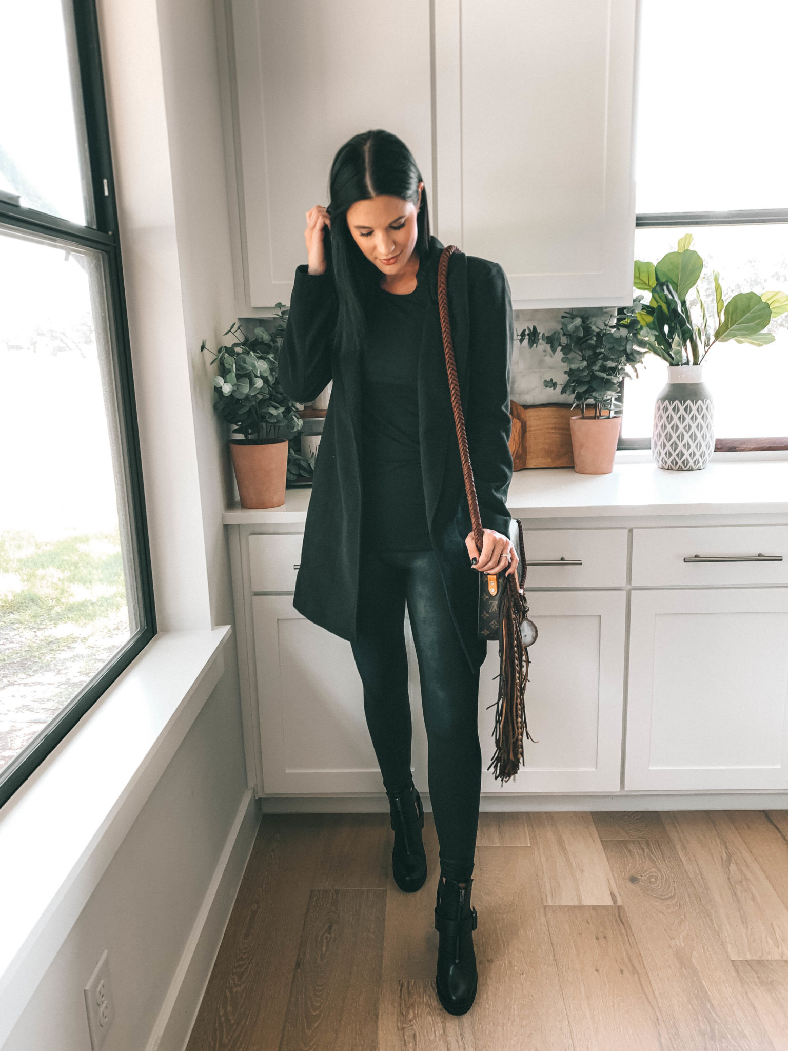How to Style an All Black Outfit 3 Different Ways by popular Austin blog, Dressed to Kill: image of woman standing in her kitchen and wearing a black Halogen Double Face Coat, black Spanx Faux Leather Leggings, and carrying a World Traveler Dirty Blonde purse.