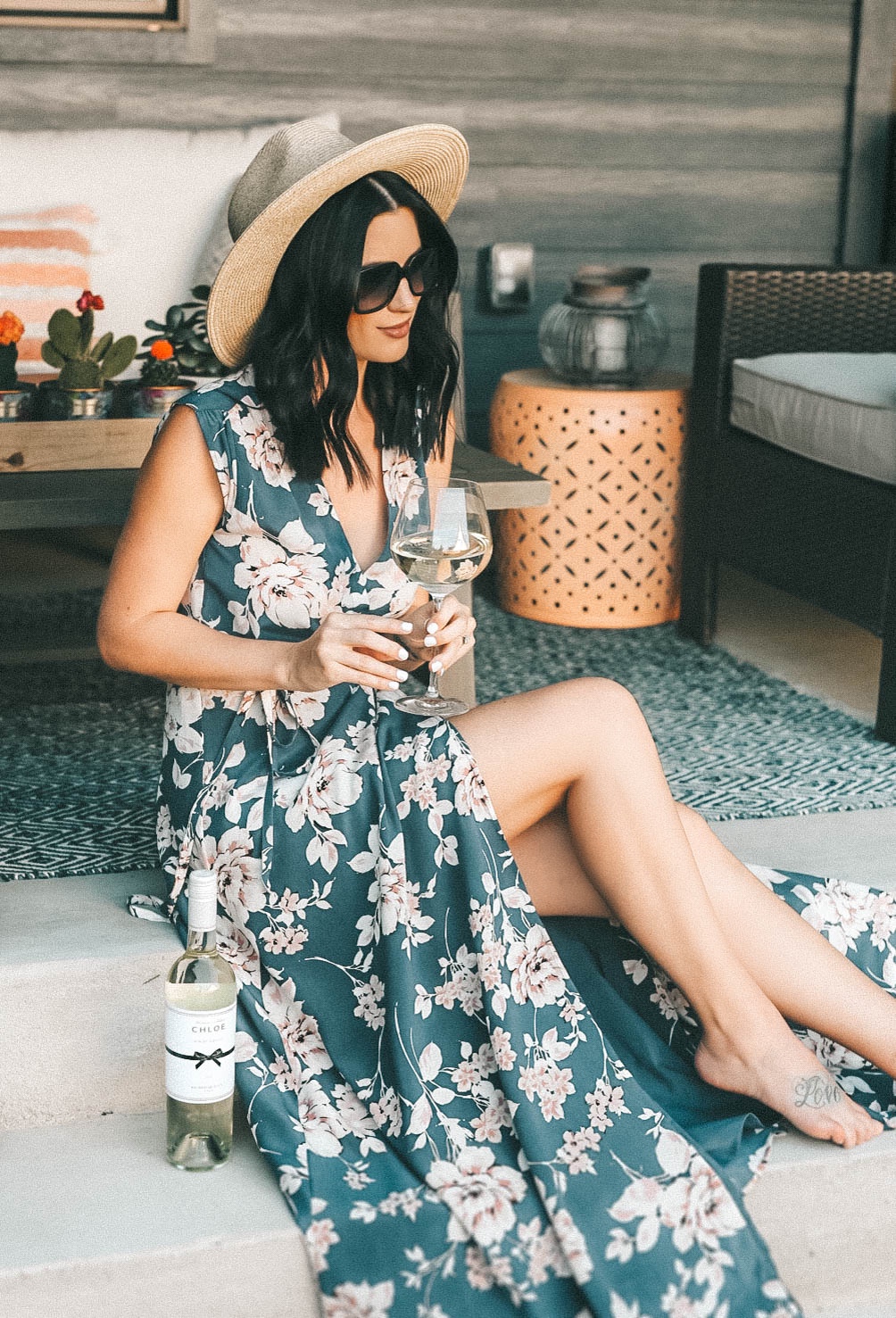 Celebrating Women in Film with Chloe Wine Collection by popular Austin life and style blog, Dressed to Kill: image of a woman sitting outside on her patio next to a bottle of Chloe pinot grigio wine and holding a wine glass in her hand that's half full with the same wine.