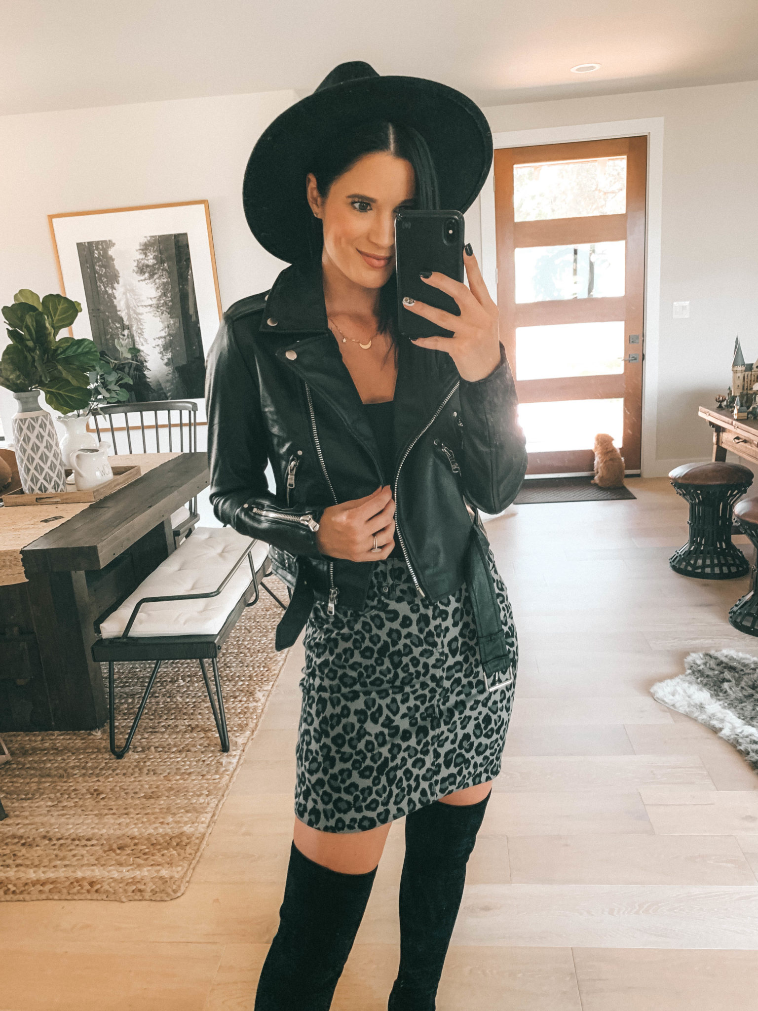 7 Affordable Fall Outfits from Walmart by popular Austin fashion blog, Dressed to Kill: image of a woman standing inside her house and wearing a black Walmart Sofia Jeans Cold-Shoulder Ruffle Neck Woven Top, Sofia Jeans Margarita Leopard Print Pencil Skirt, and Celsius Women's Faux Leather Moto Jacket.