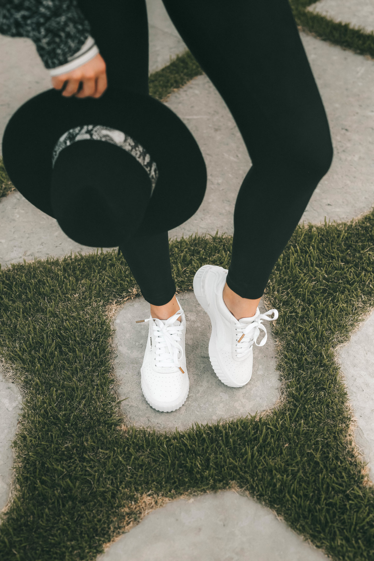How to Wear White Sneakers by popular fashion blog, Dressed to Kill: image of a woman wearing a TopShop black and white sweater, black felt hat, black leggings, and white Puma sneakers.