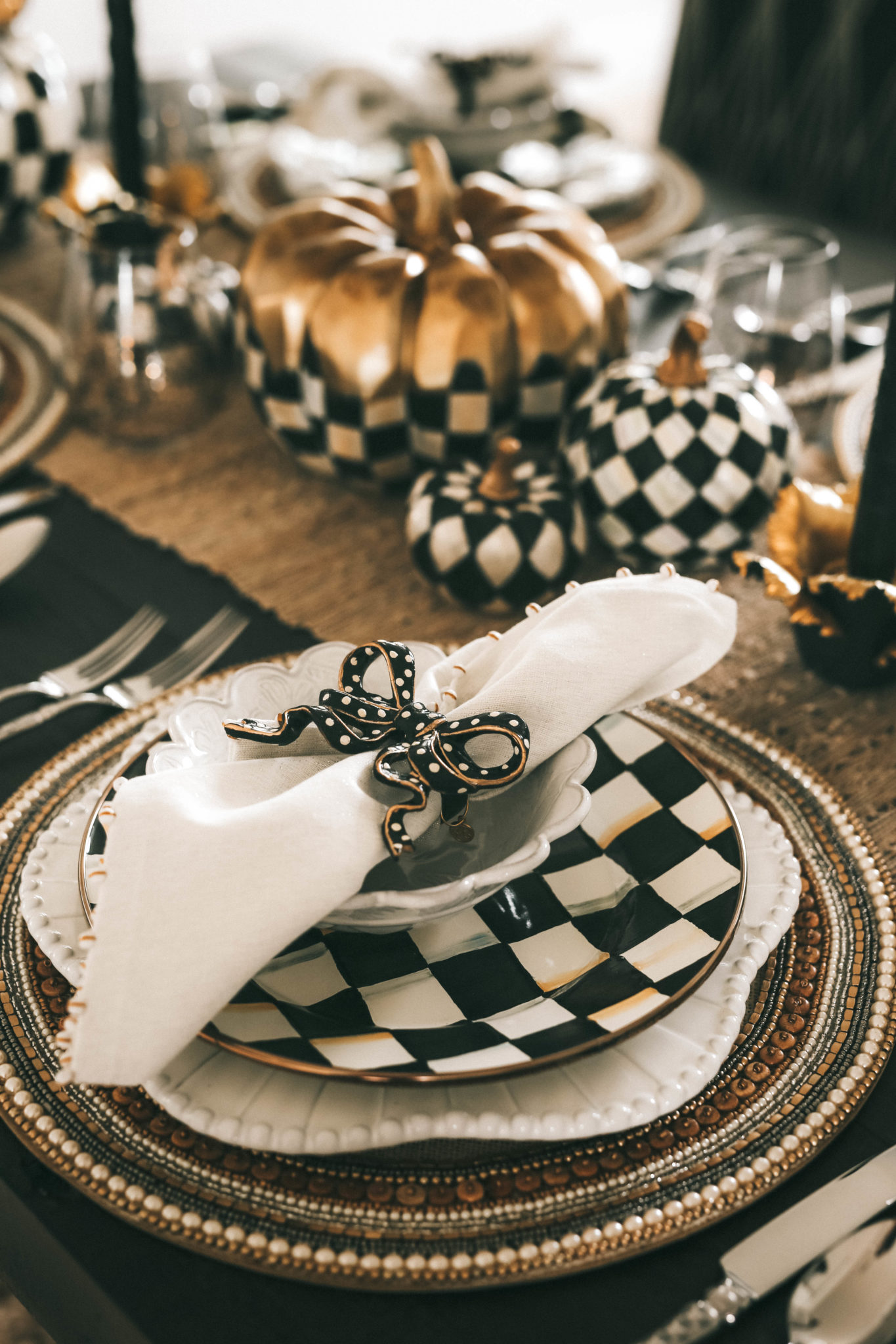 Decorating with MacKenzie Childs Fall Collection by popular Austin life and style blog Dressed to Kill: image of a table decorated with MacKenzie Childs Courtly Check and Harlequin pumpkins, Jeweled Circle Placemats, Sweetbriar chargers, Courtly Check dinner plates, Daffodil Candle Holders, raised check dinner candles, Sweetbriar small bowls, bow napkin rings, ivory napkins and check flatware.