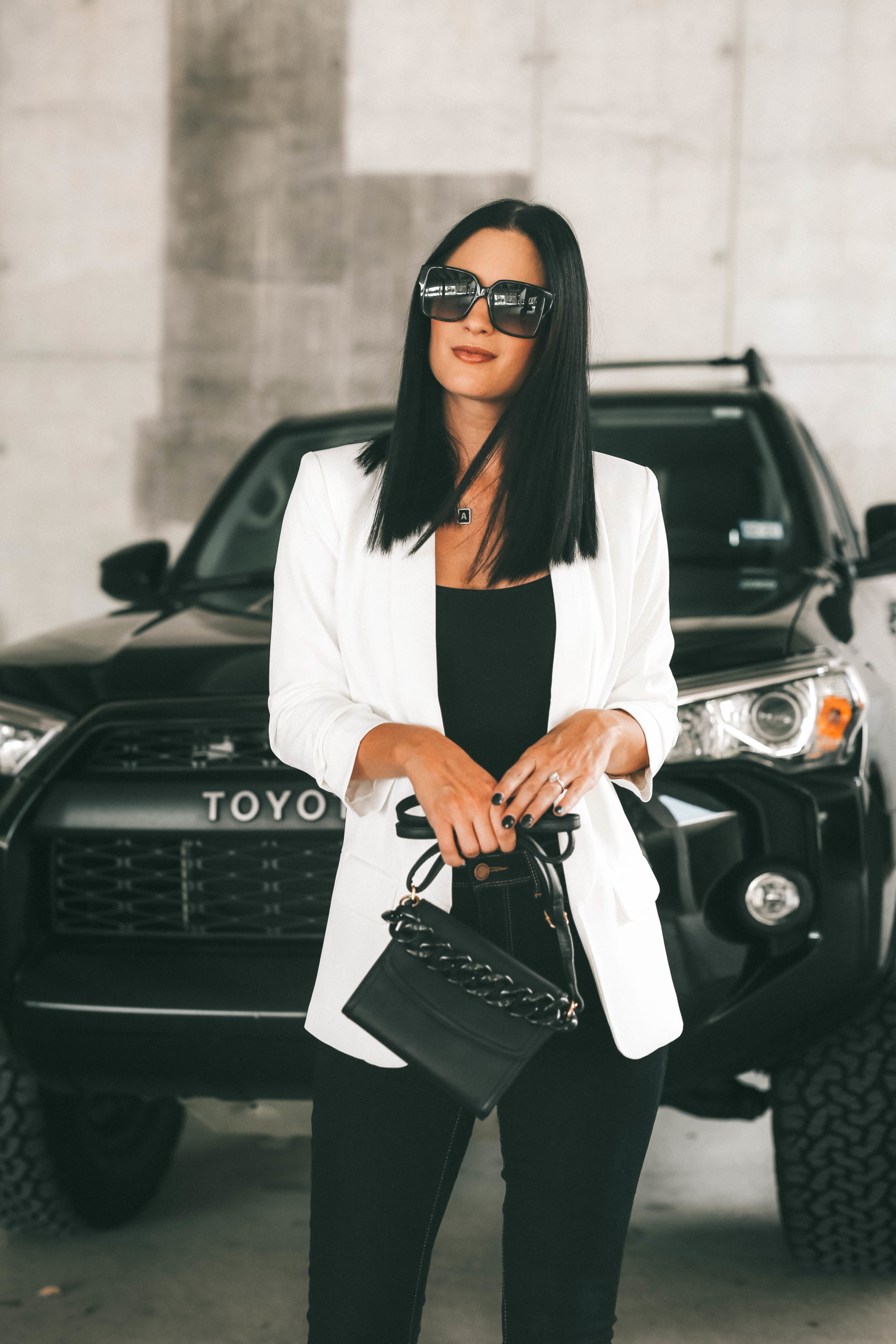 Blazer for Women by popular Austin fashion blog, Dressed to Kill: image of a woman standing in front of her black Toyota car and wearing a Walmart Scoop Scrunch Sleeve Shawl Collar Blazer, Jordache Women's Essential High Rise Super Skinny Jean, Guess Womens Simi Adjustable Straps V-Back Bodysuit, black frame sunglasses, and holding a black purse. 