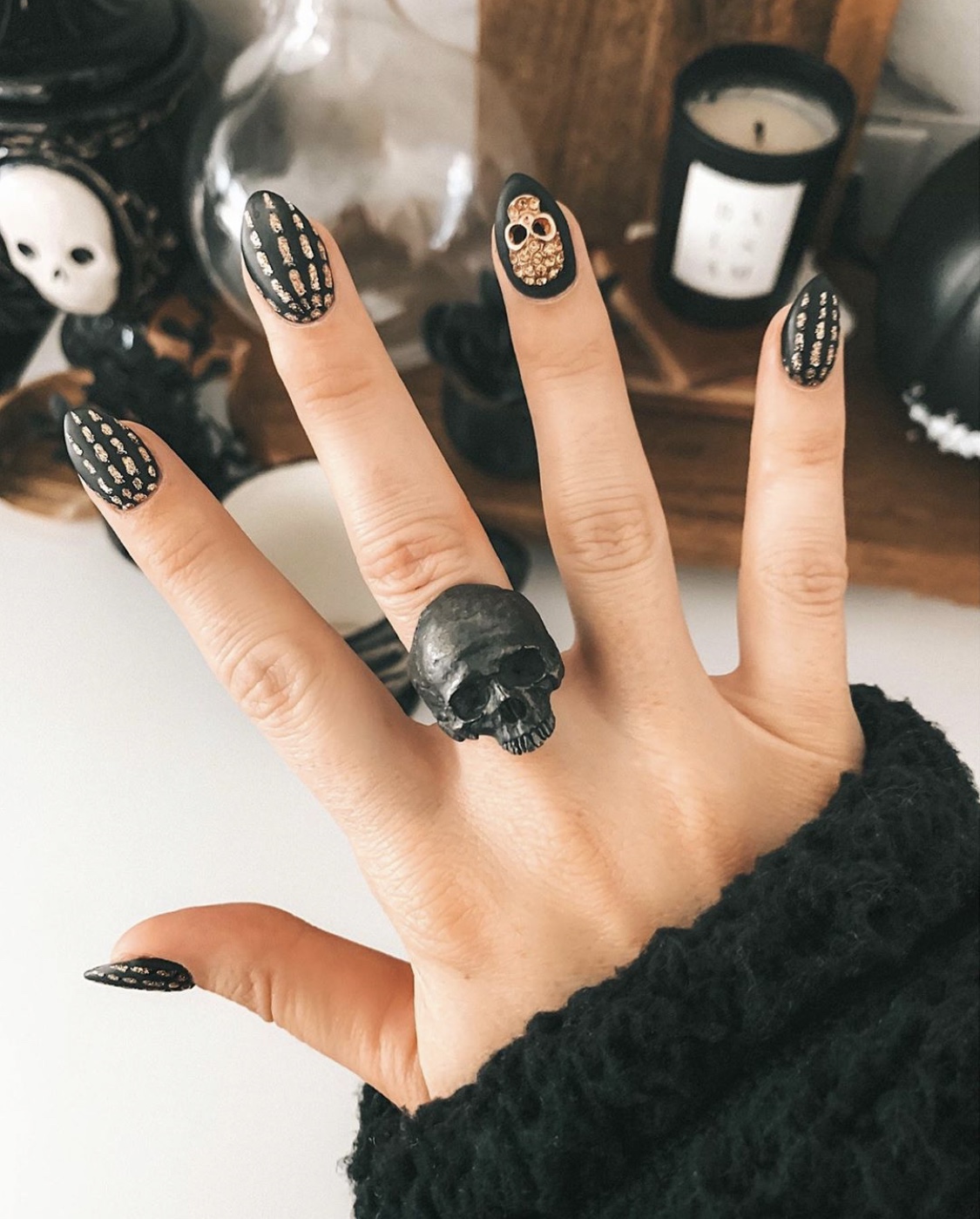 Nail Art Designs by popular Austin beauty blog, Dressed to Kill: image of a woman with gold and black skeleton design nail art and wearing a Into the Fire skull ring. 